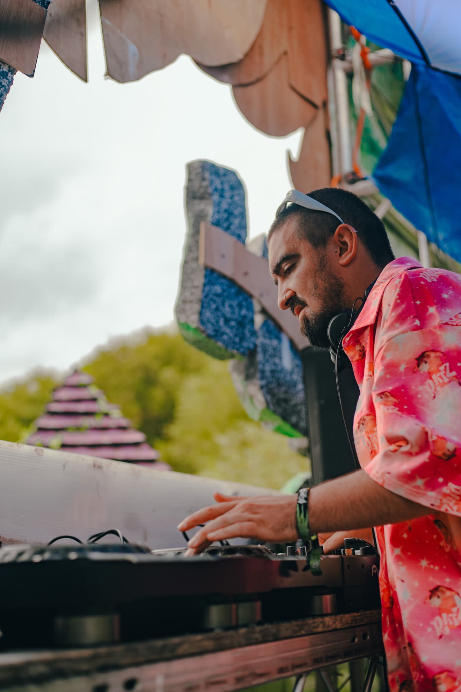 DJ in a pink shirt performing on an outdoor stage