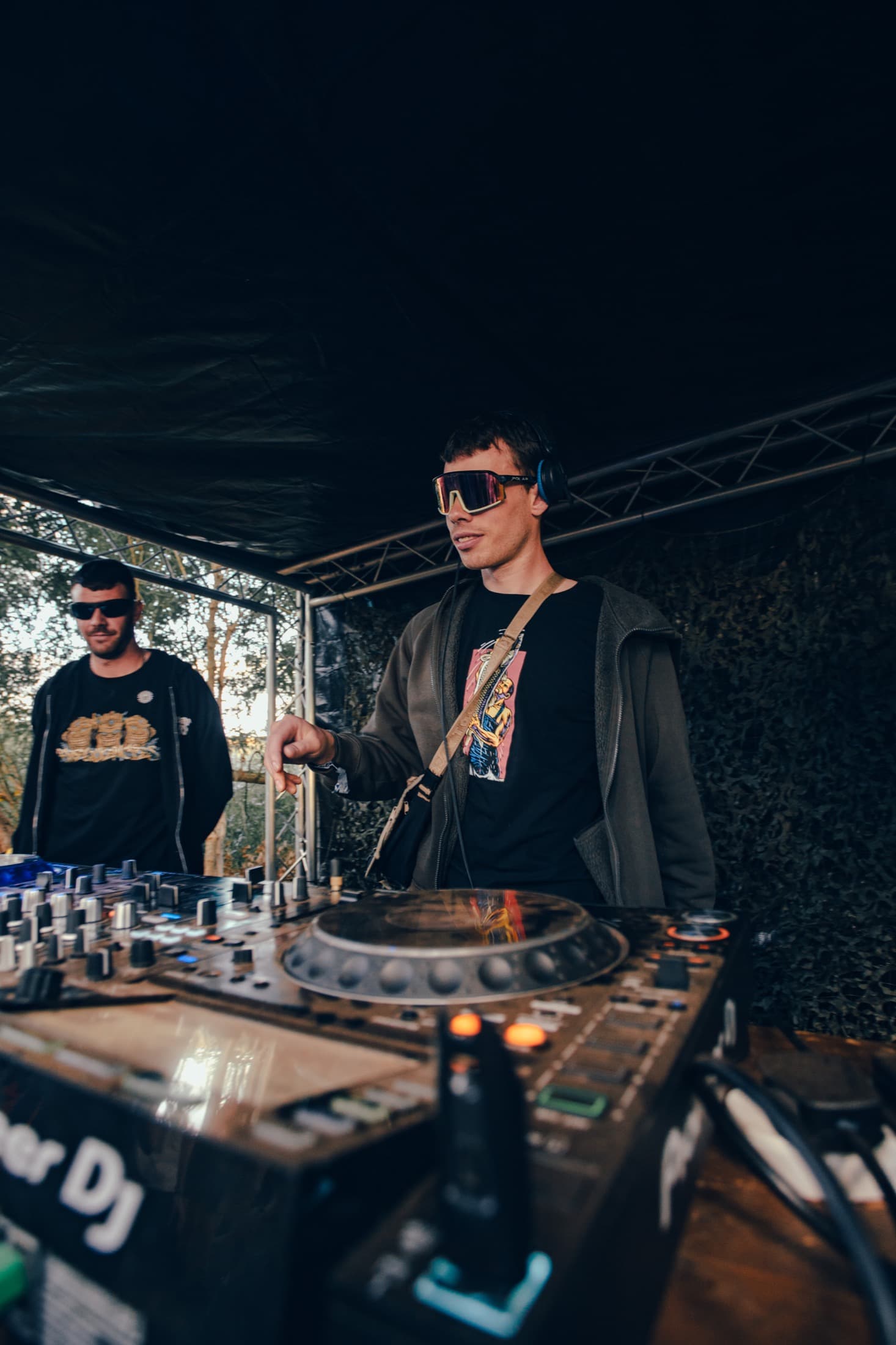 DJs performing behind decks under a stage canopy
