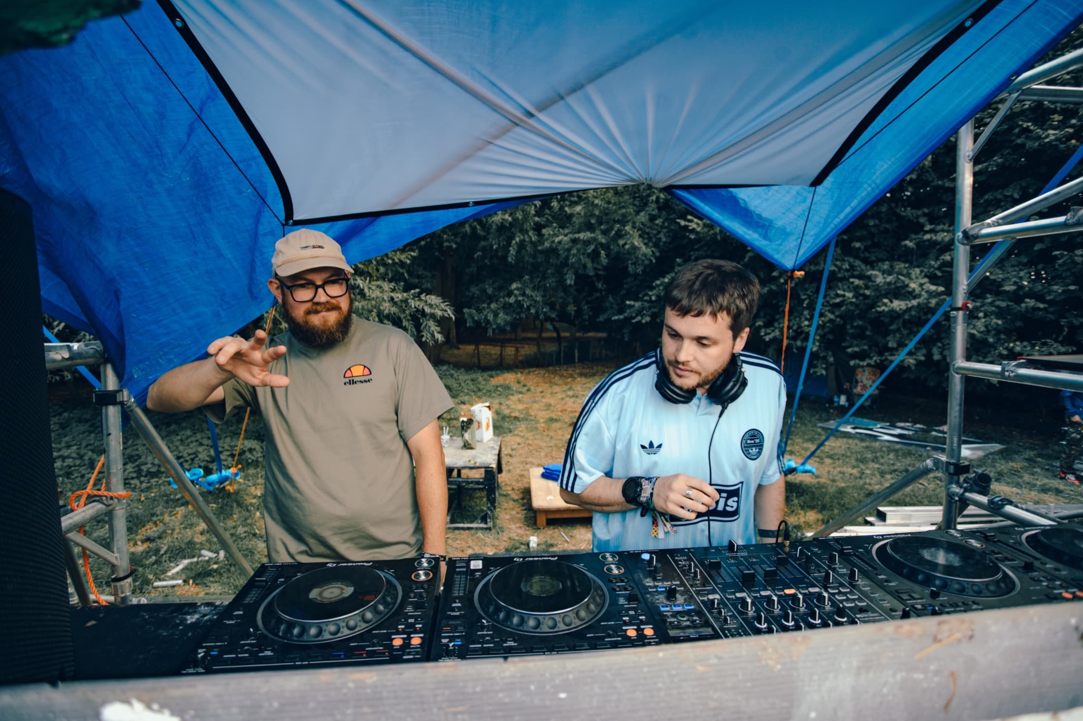 Two DJs under a blue festival canopy
