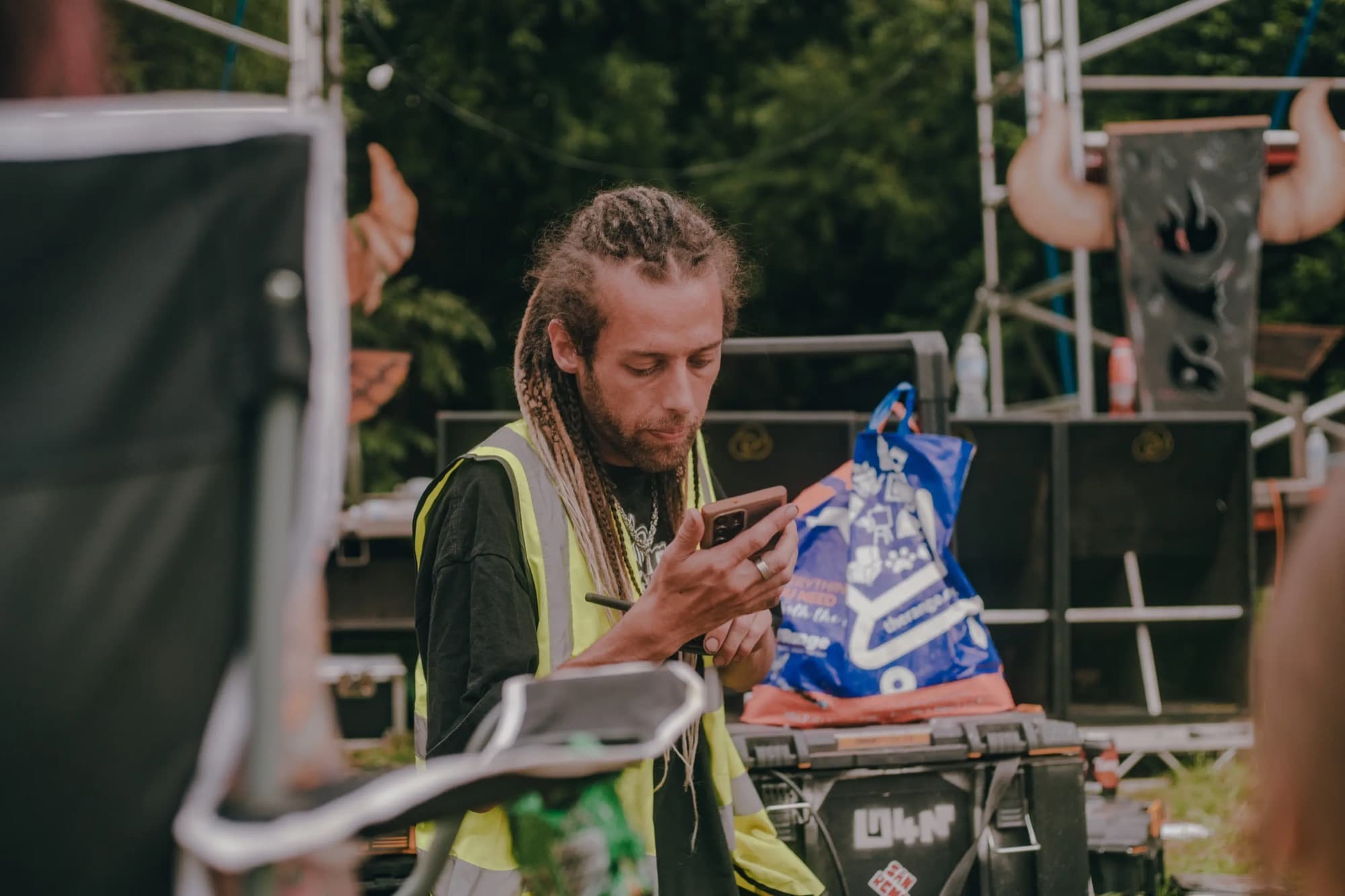 A crew member in a hi-vis vest checking their phone on site at Slipshod Gathering